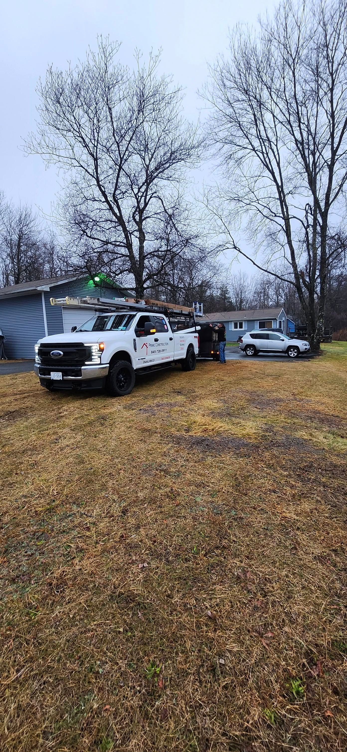 A white truck is parked in the grass in front of a house.