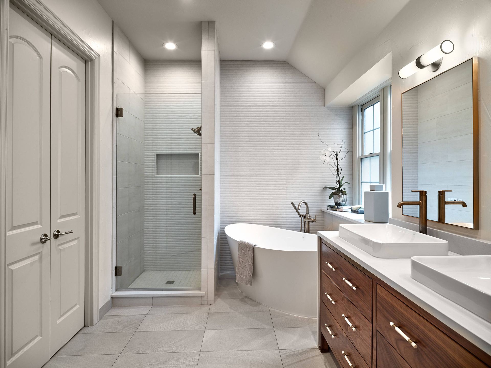 A bathroom with a tub, sinks, and a walk in shower.