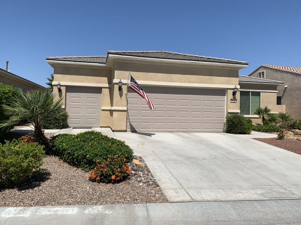 A house with two garage doors and an american flag in front of it