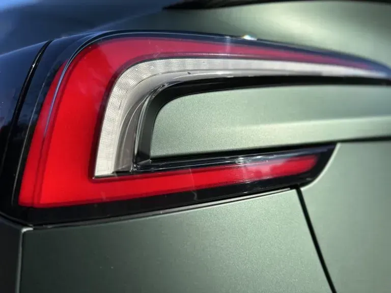 Close-up of a car’s red and white taillight on a gray vehicle.