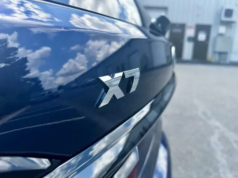 Close-up of a glossy black BMW X7 badge on the rear of a car.