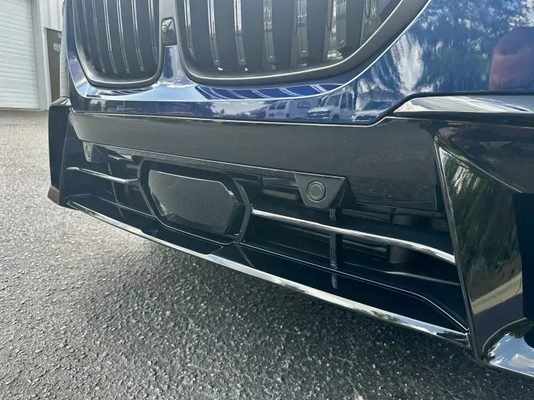Close-up of a blue BMW front grille and bumper with a centered license plate mount.