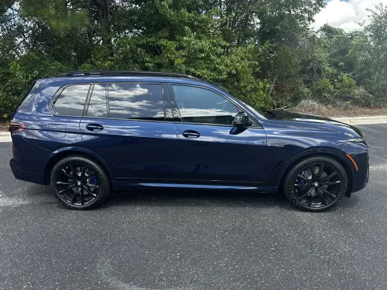 Dark blue SUV parked on a road with trees in the background