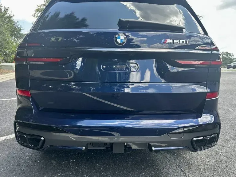 Rear view of a blue BMW SUV parked outdoors, showing BMW and M50i badges.