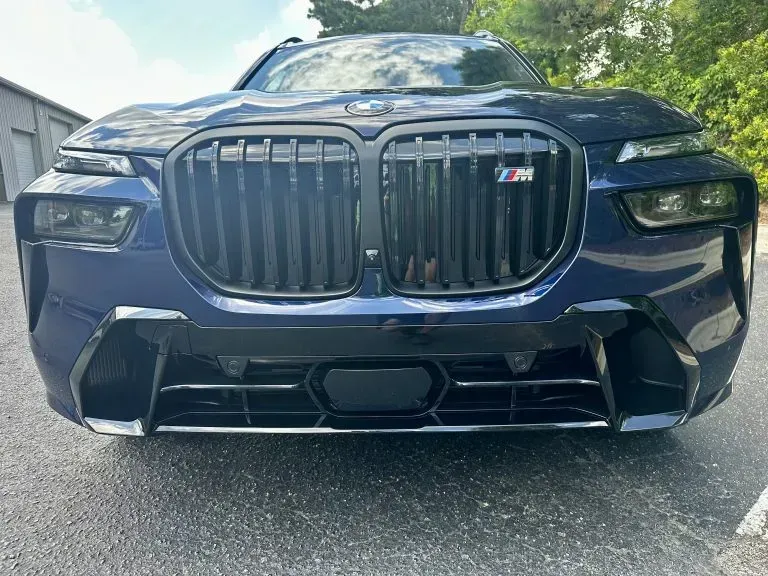Front view of a dark blue BMW SUV with a large grille parked on a road