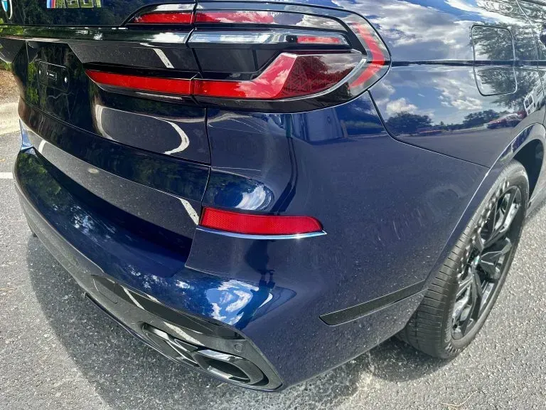 Rear corner of a dark blue SUV, showing taillight, rear bumper, and wheel.