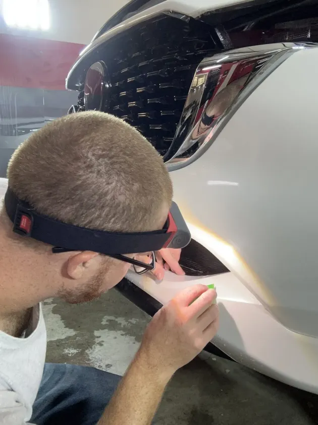 Gloved hands inspecting a black metal rim in a workshop