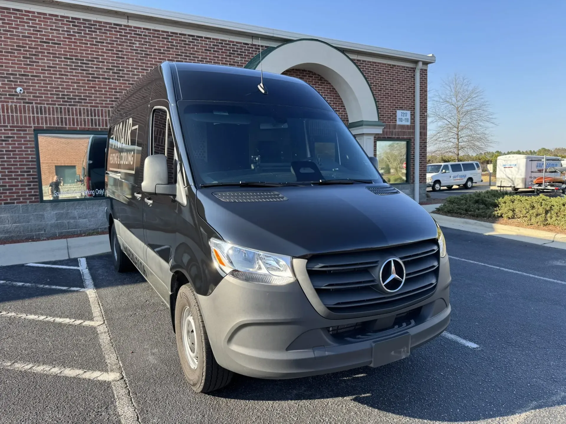 Gray Mercedes van parked outside a brick building on a sunny day