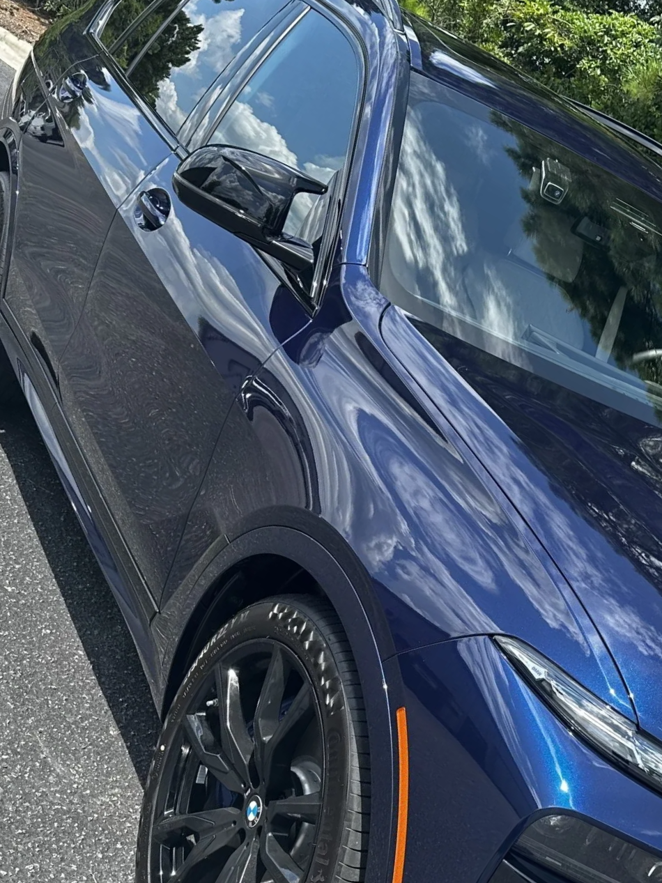 Blue SUV parked outdoors with reflections on the windows and black wheels