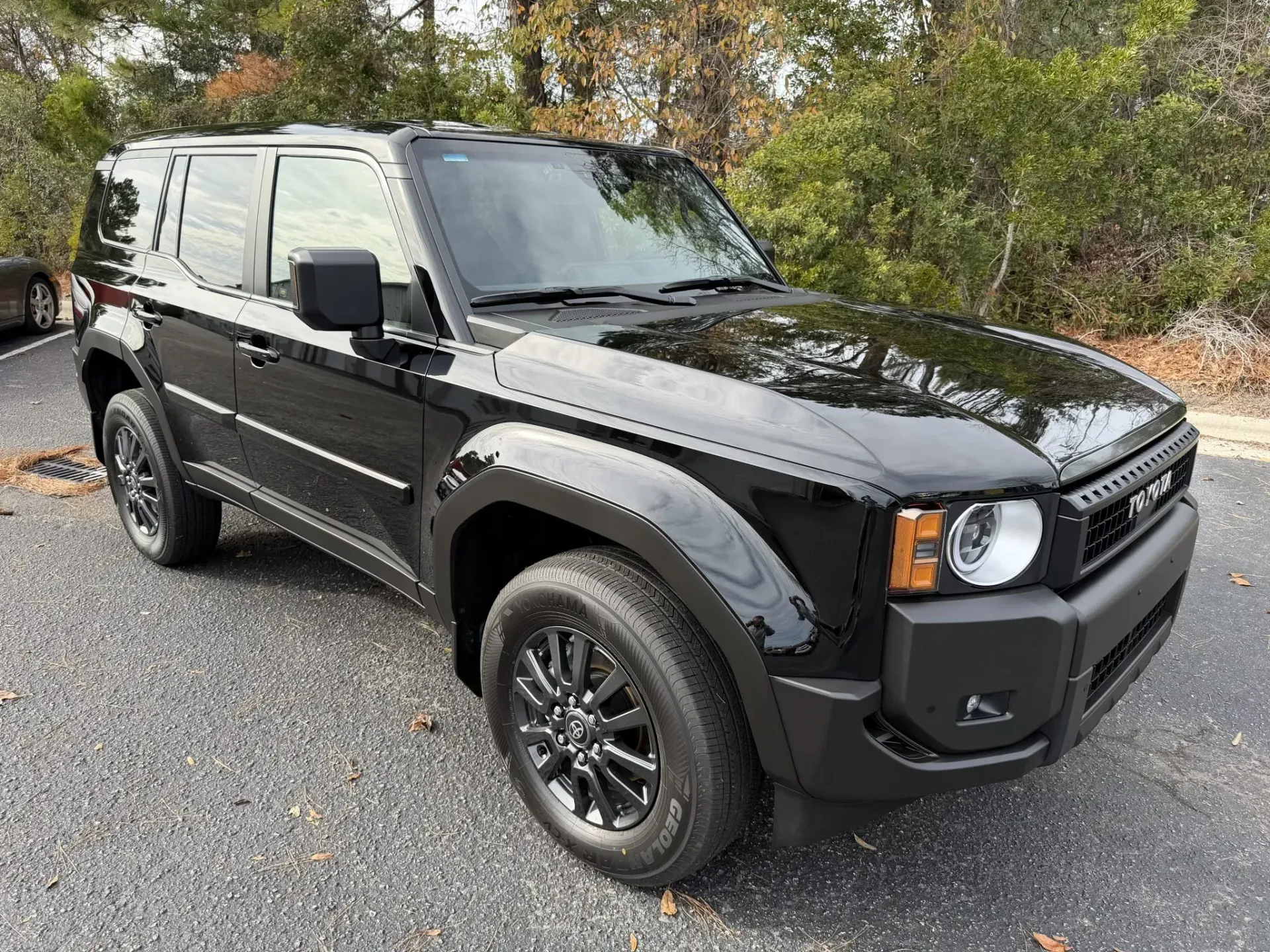 Black Ford Bronco parked on gravel with trees in the background