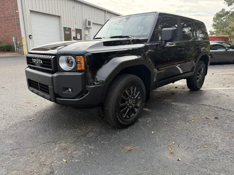 Black Toyota SUV parked outside a building on a wet driveway