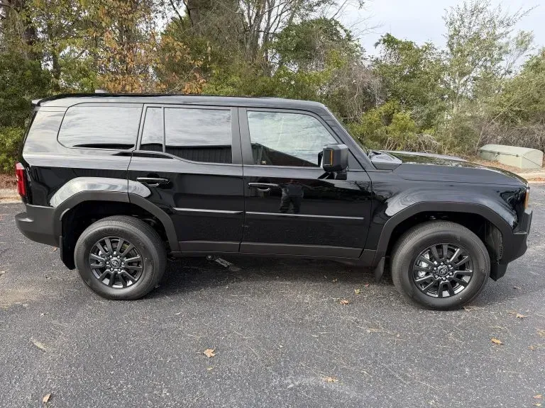 Black SUV parked on a paved road with trees in the background