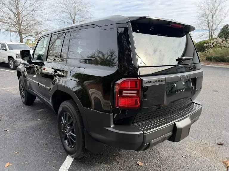 Black SUV parked in a lot, rear three-quarter view, with tinted windows and black wheels.