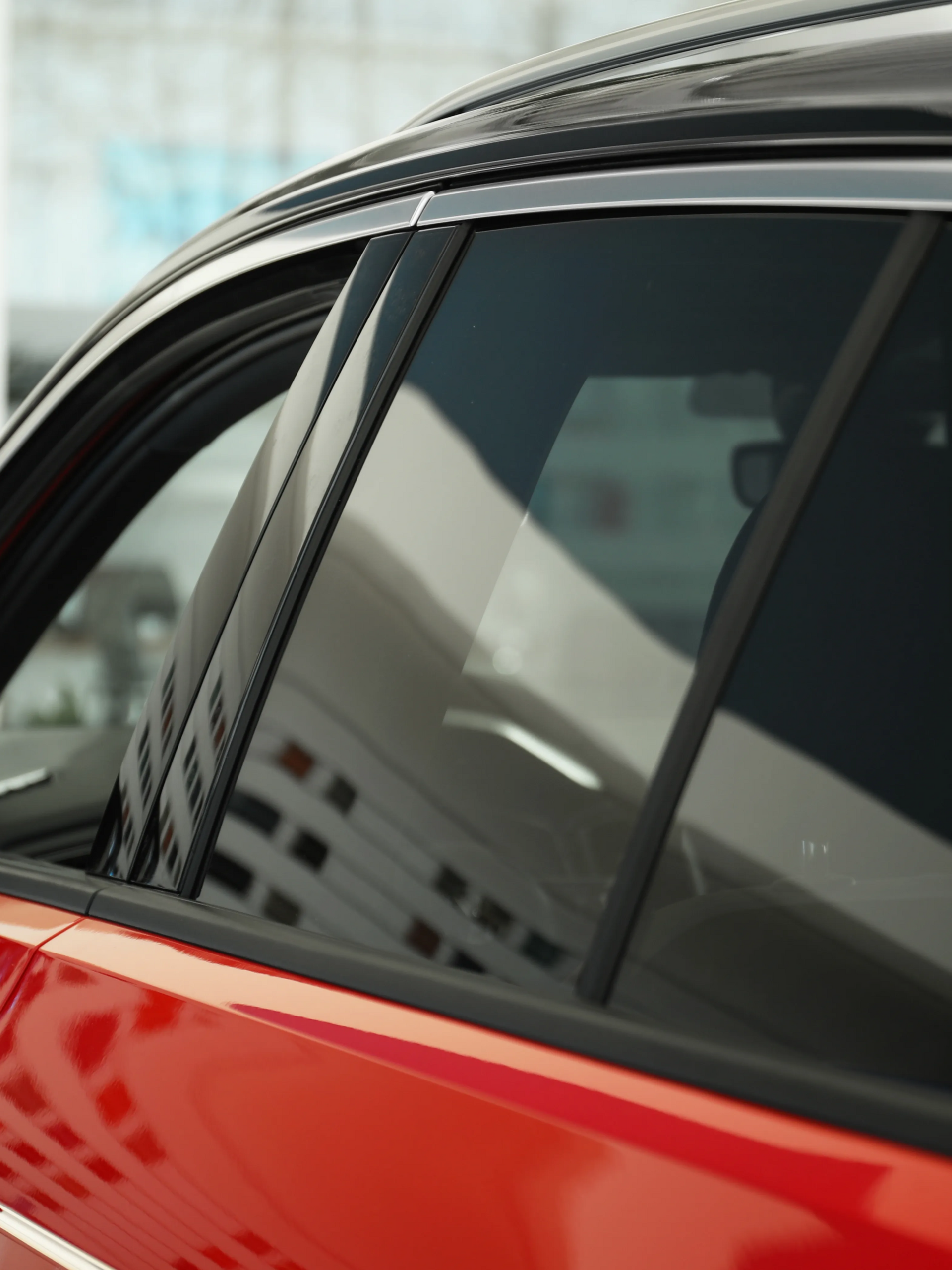 Close-up of a red car door and tinted window with black trim