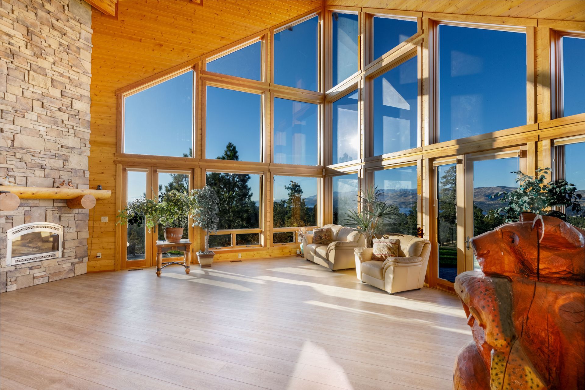 Modern glass house at sunset with warm interior lights and landscaped garden outside