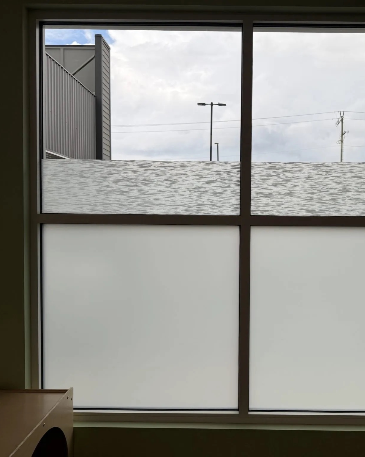 Frosted window with a snowy ledge and cloudy sky outside, viewed from indoors