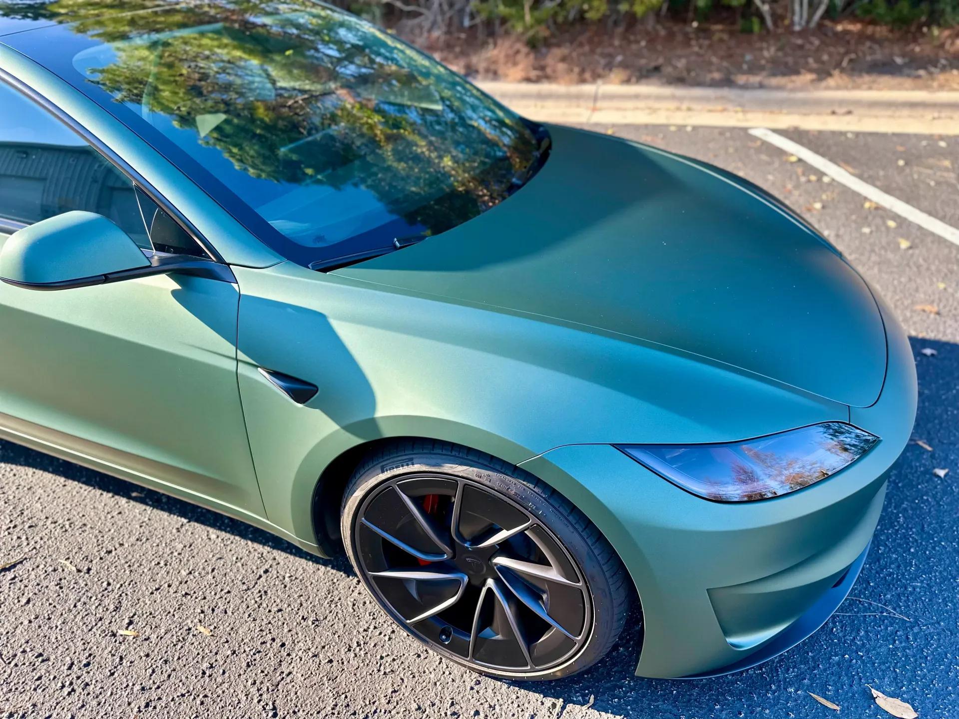Teal sports car parked on a sunny road, front-left view with reflections on the windshield