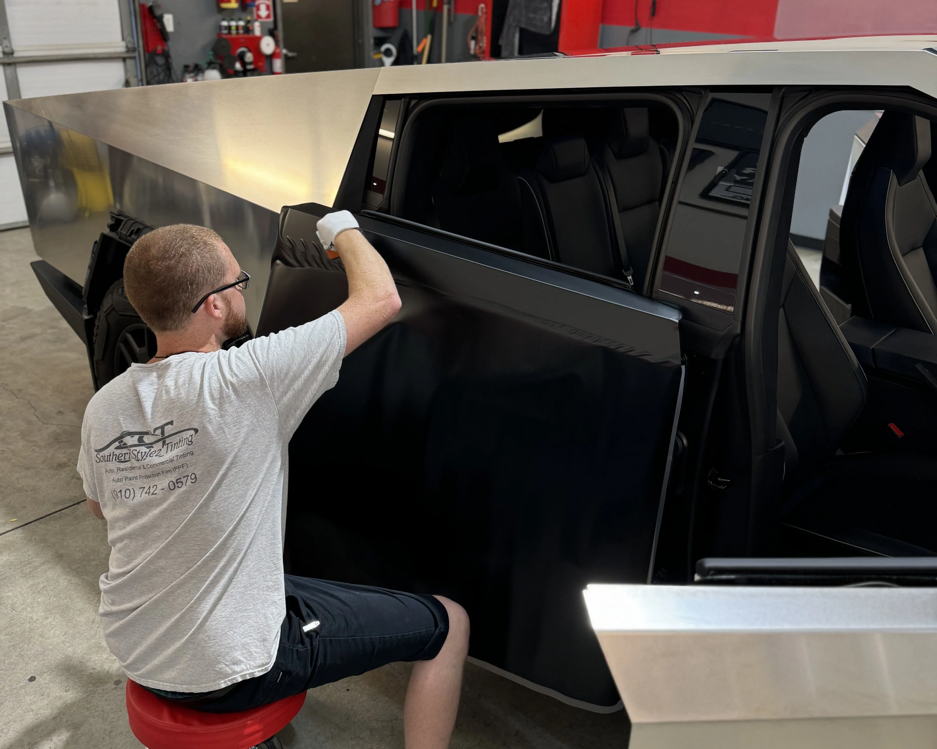 Person installing a black panel on a vehicle in a workshop