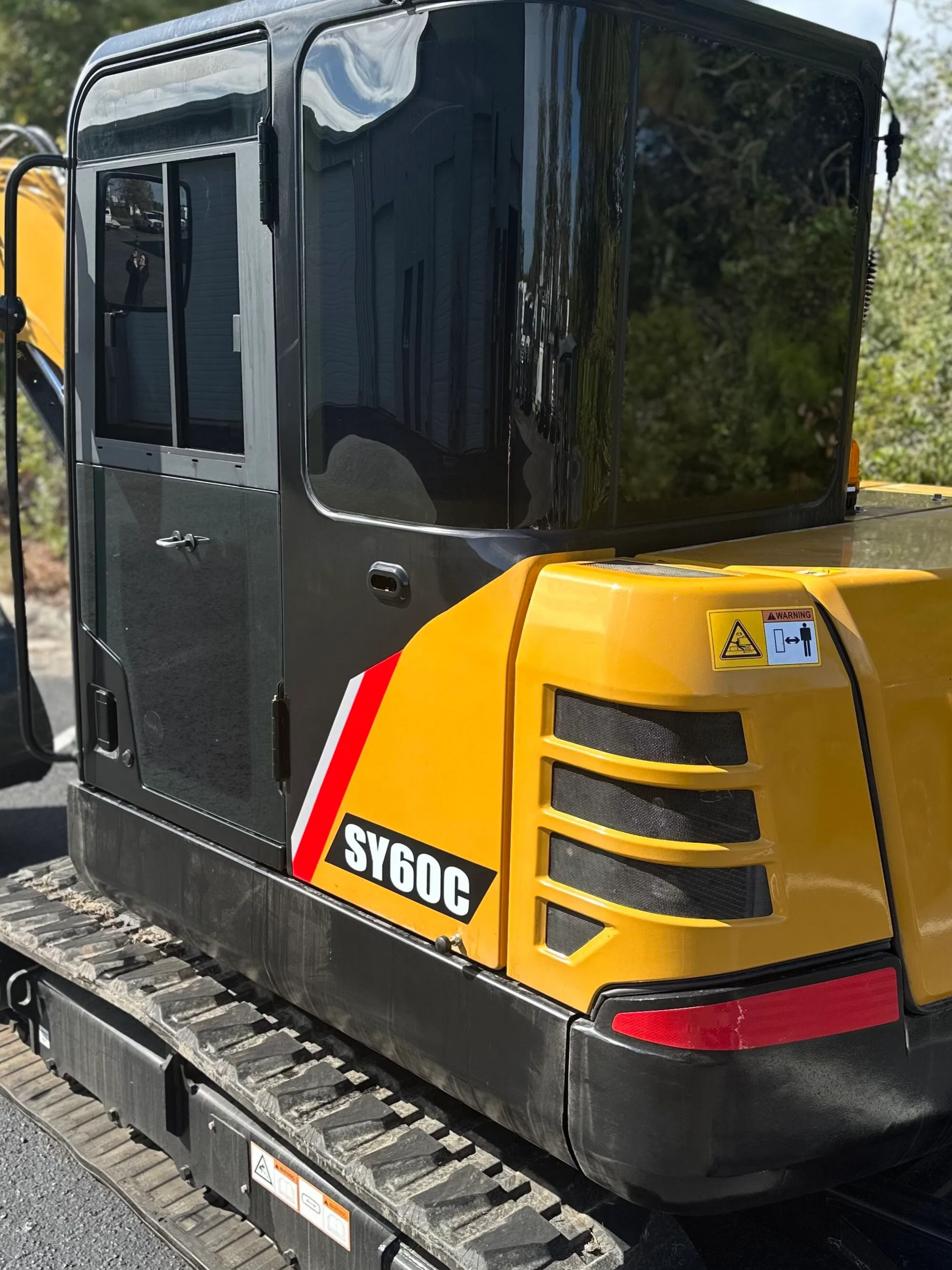 Black and yellow compact excavator parked outdoors, side view with tracked base and cab visible
