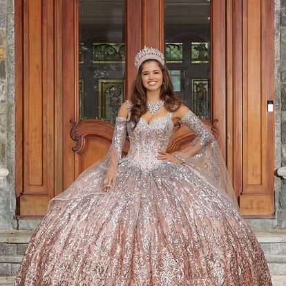 A woman in a ball gown and tiara is standing in front of a door.