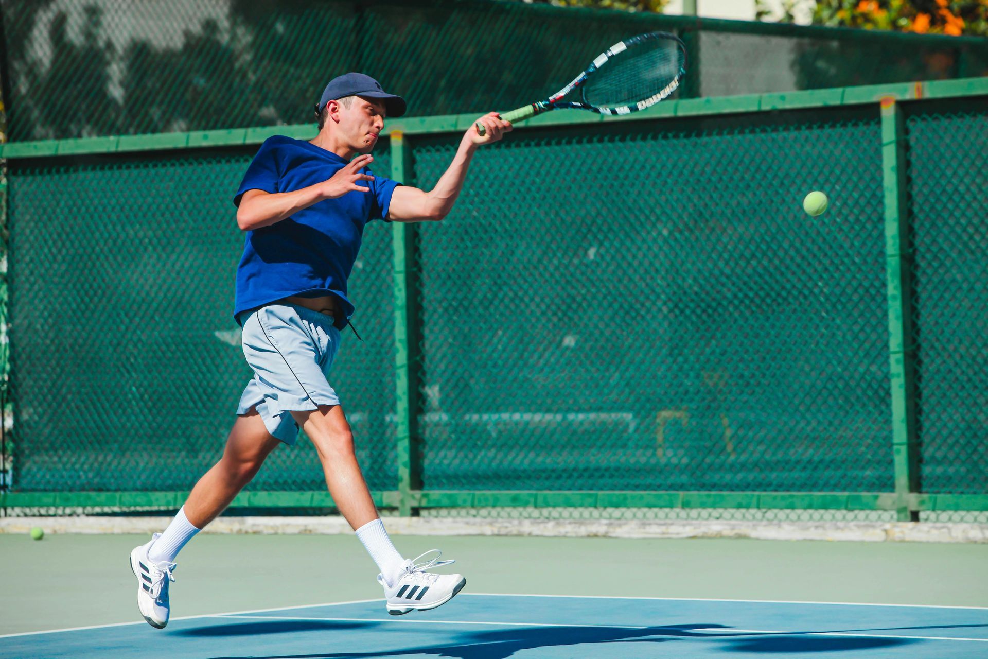 Tennis ball at the corner of a green and blue court, white line.