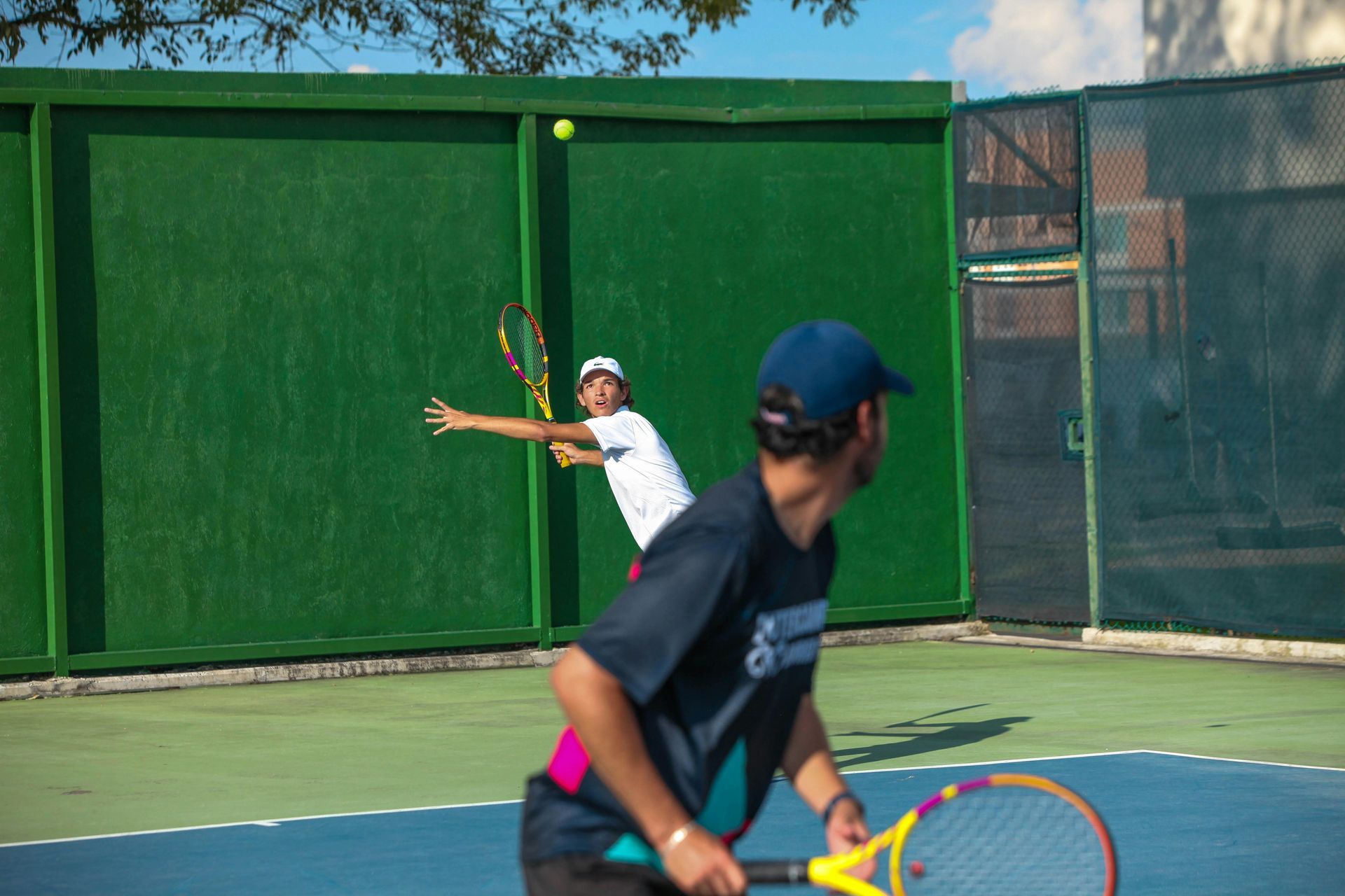 Tennis ball at the corner of a green and blue court, white line.