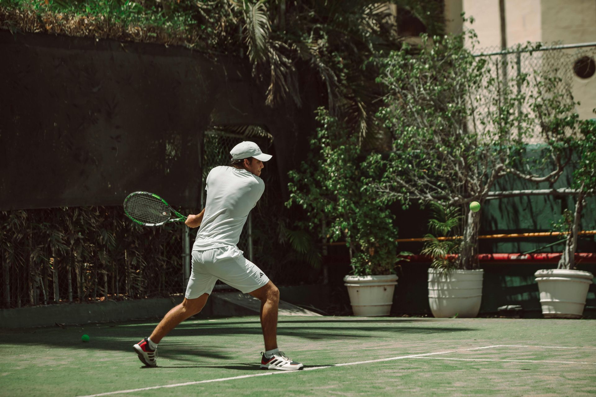 Tennis ball at the corner of a green and blue court, white line.