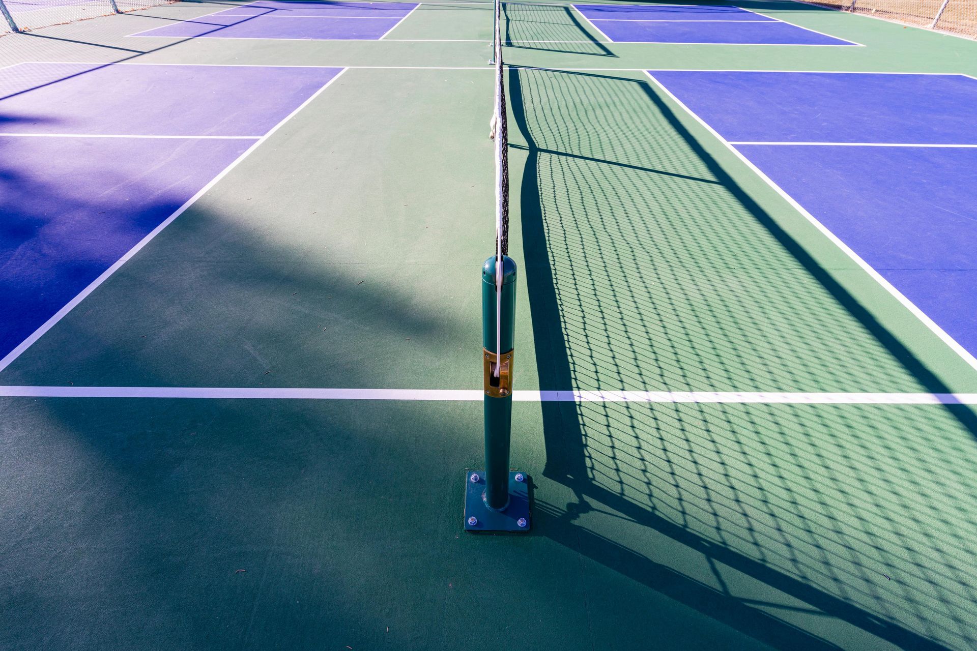 Pickleball court with net, marked with blue, green, and white lines.