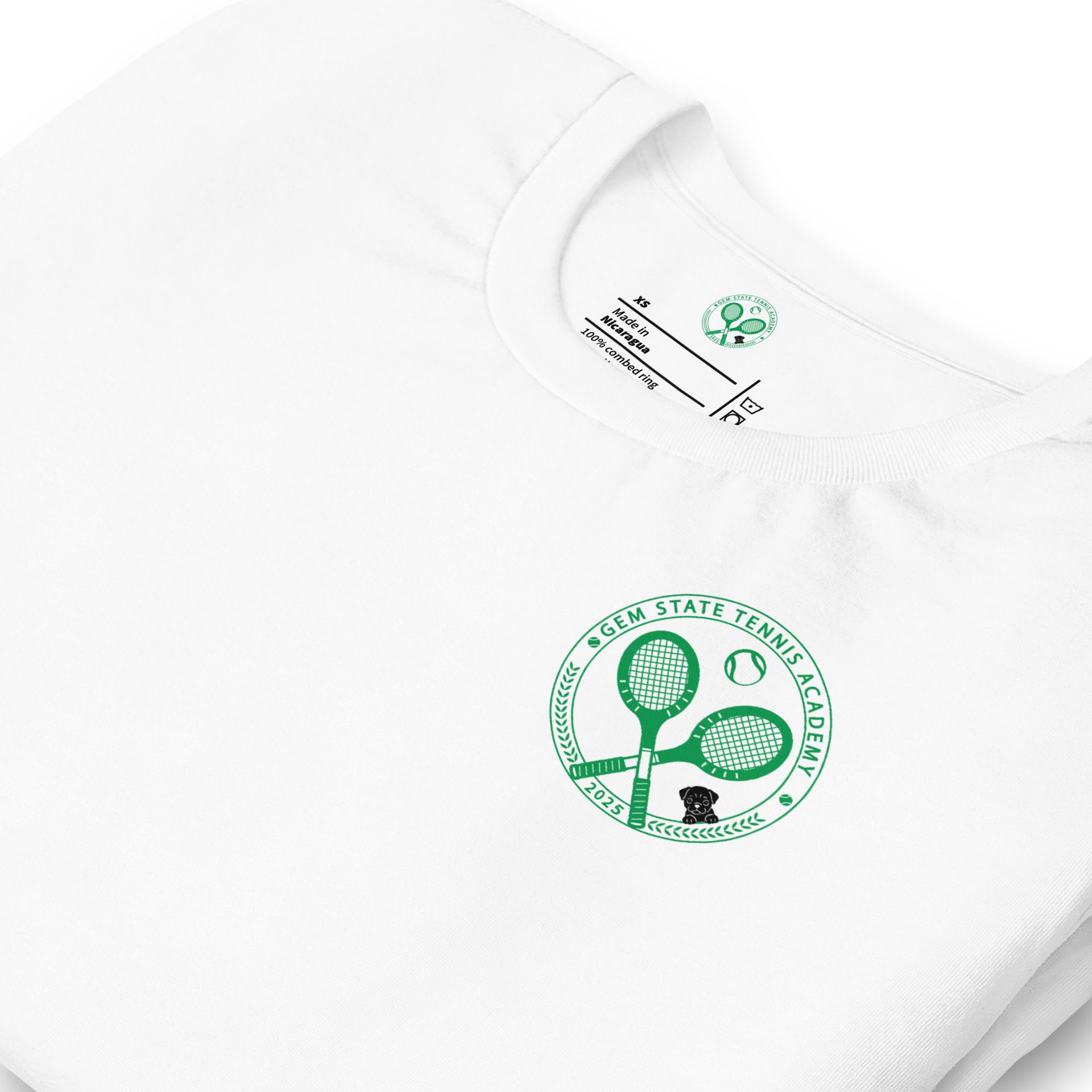 White t-shirt with a green tennis academy logo on the back. The logo has crossed rackets, a ball, and text.