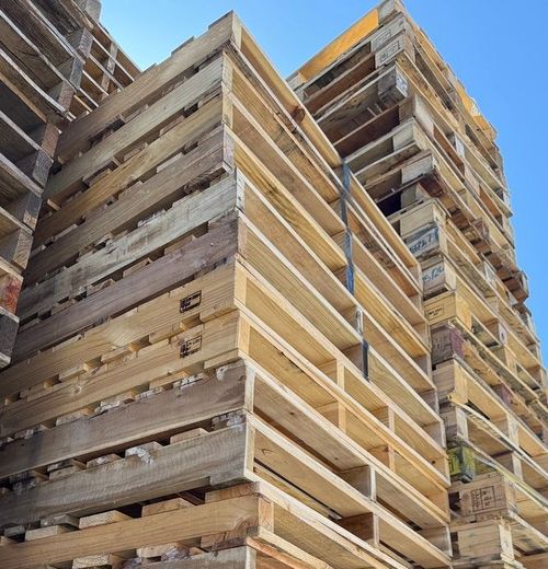 A stack of wooden pallets against a blue sky. A stack of wooden pallets against a blue sky.