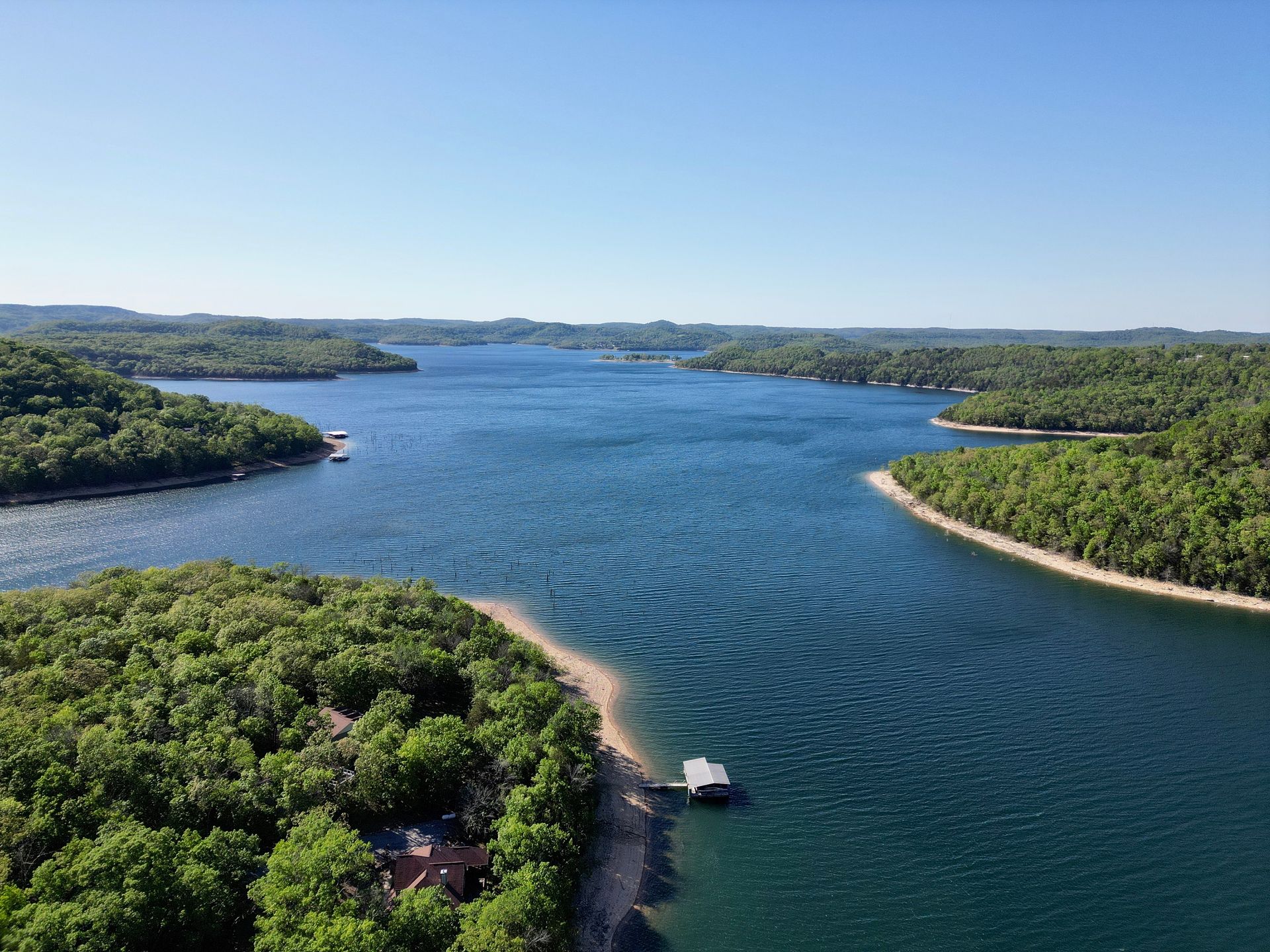 Wide river winding through green islands under a clear blue sky, viewed from above
