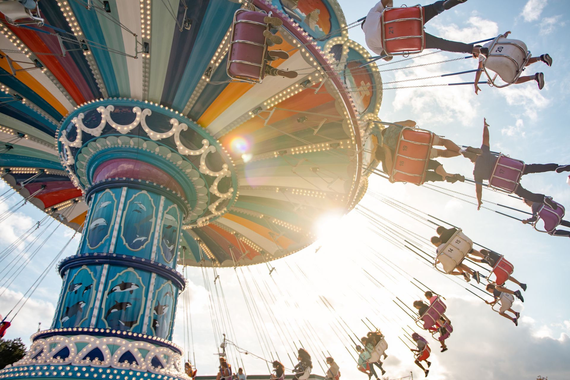 Colorful swing ride spinning at an amusement park with riders against a bright sky