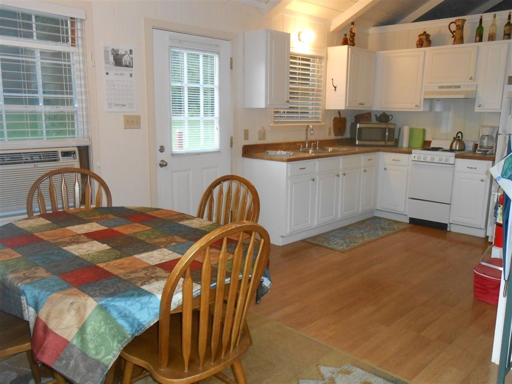Kitchen with white cabinets, wooden table, checkered tablecloth, and hardwood floor