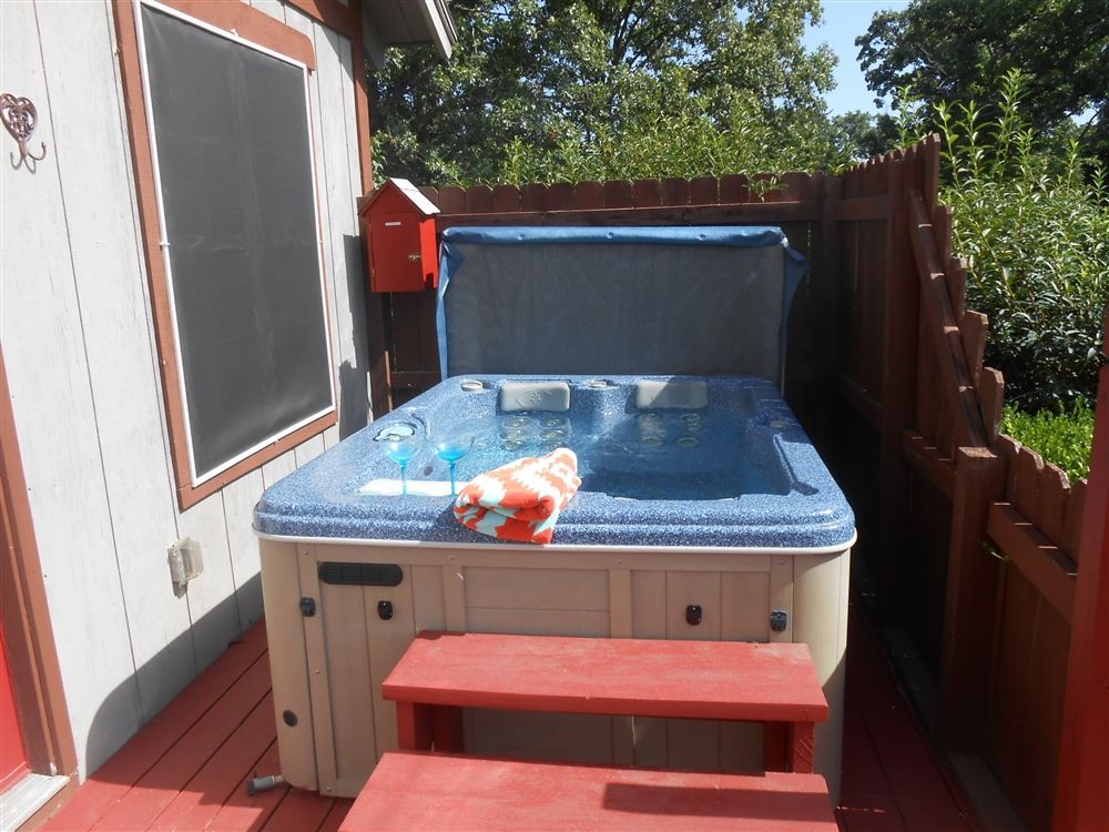 Hot tub on a wooden deck with a red bench and towels nearby