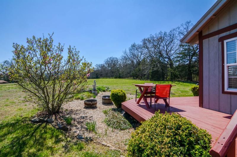 Backyard deck with red chairs overlooking a grassy yard and trees
