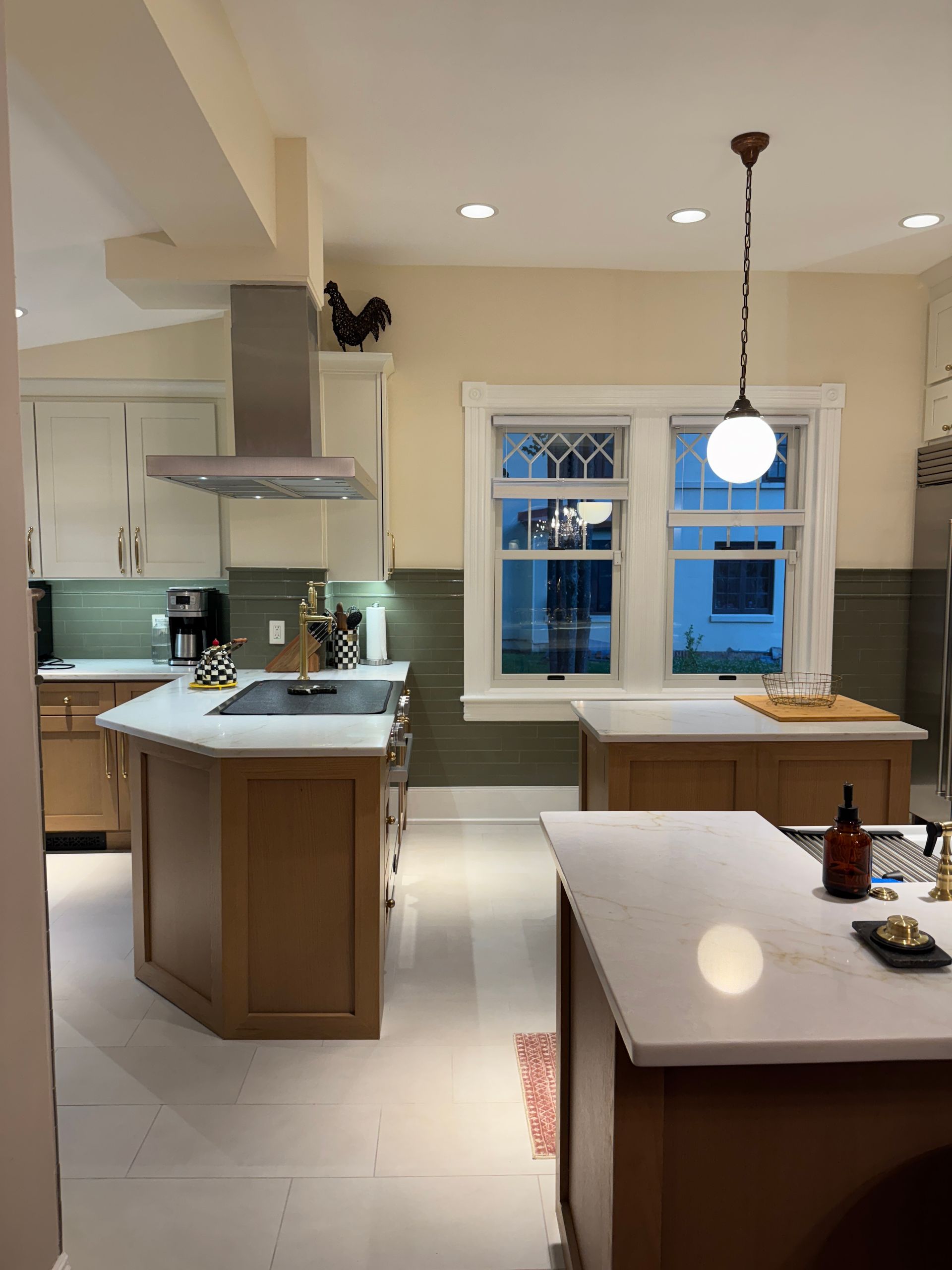 Bright kitchen with island, white cabinets, pendant light, and blue-framed window at dusk