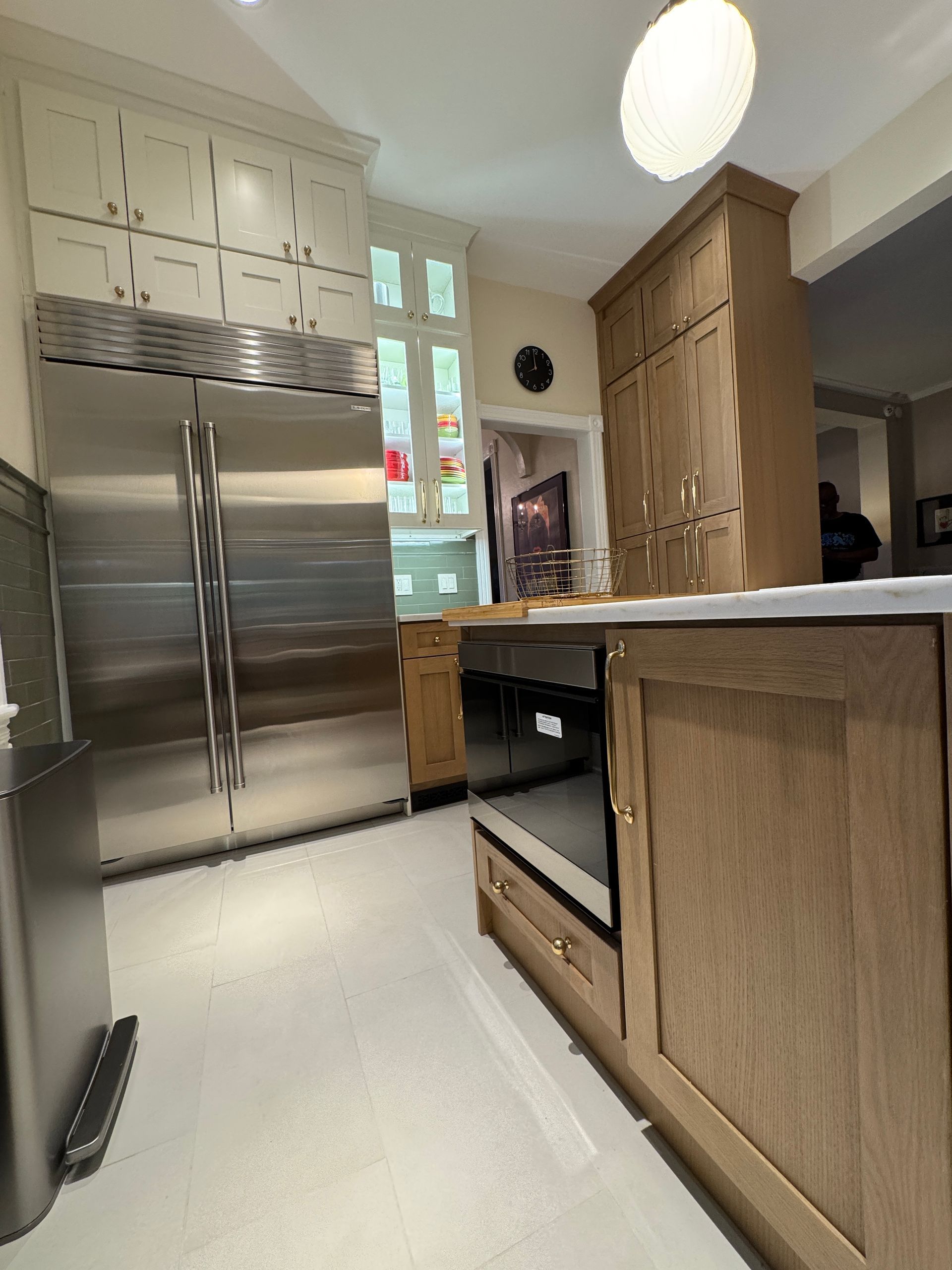 Modern kitchen with stainless steel refrigerator, white floor, and wooden island cabinets