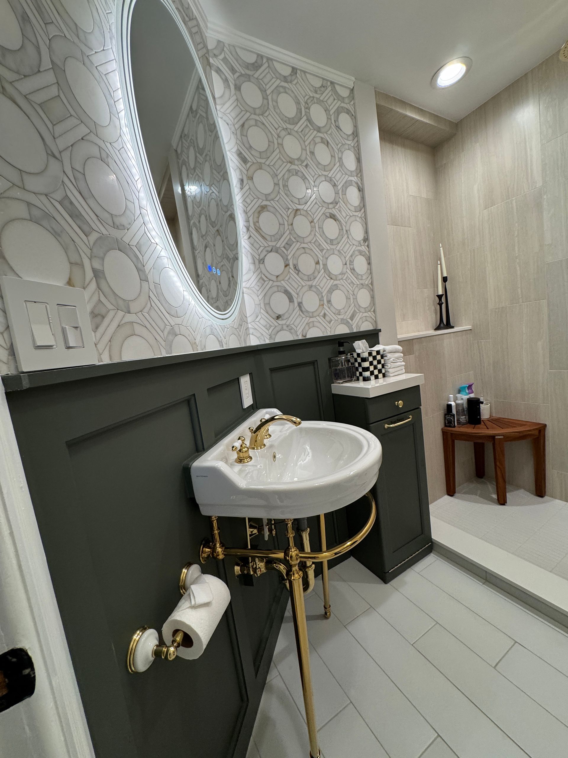 Modern bathroom with pedestal sink, oval mirror, gray walls, and white tile floor and walls