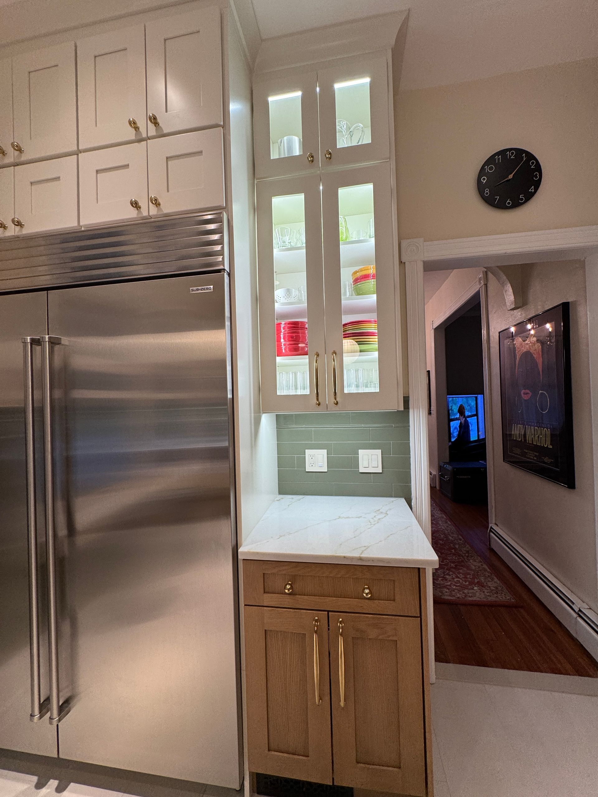 Kitchen with stainless steel refrigerator, white cabinets, and a doorway leading to a hallway and living room.