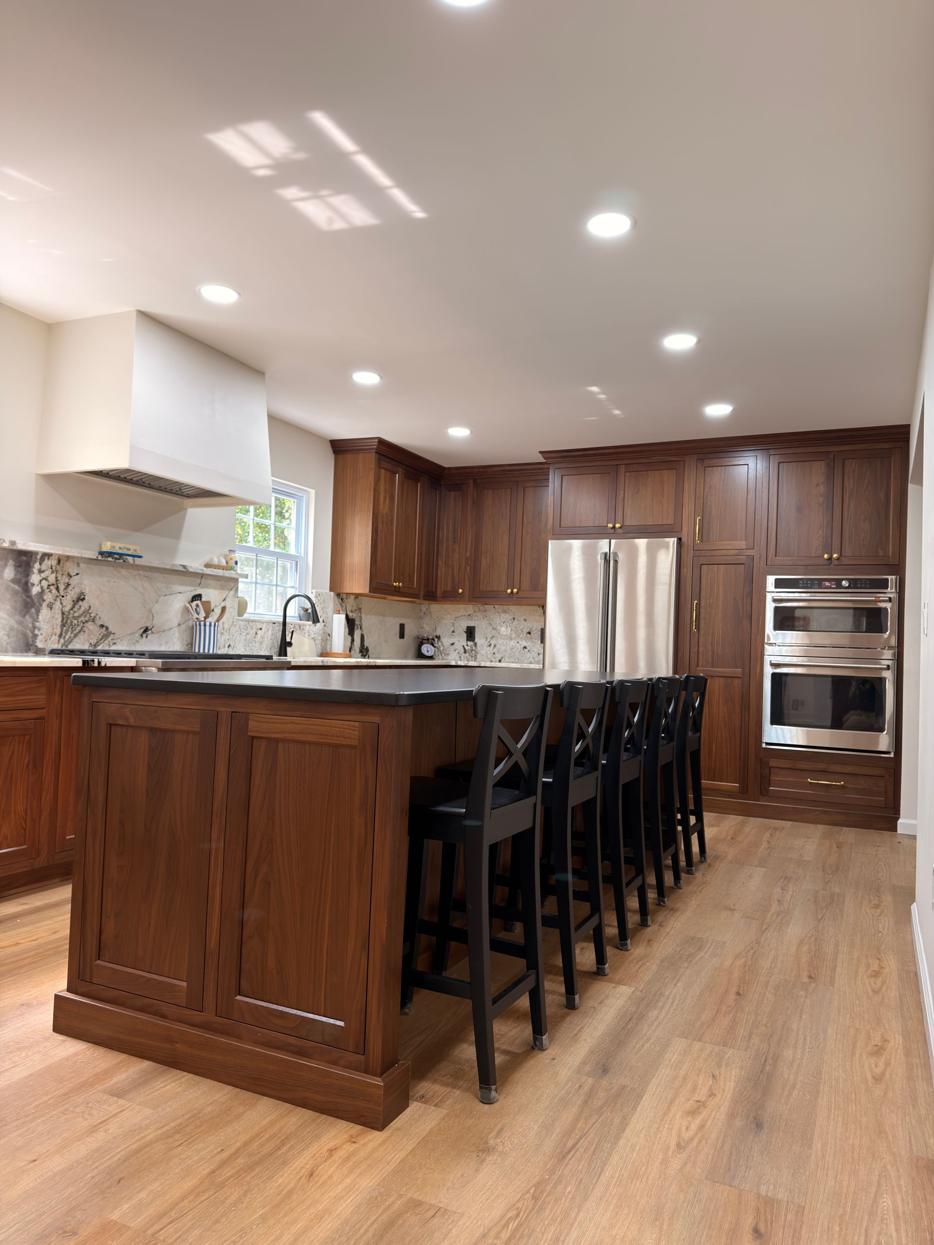 Modern kitchen with wood cabinets, stainless steel appliances, island seating, and light wood floors