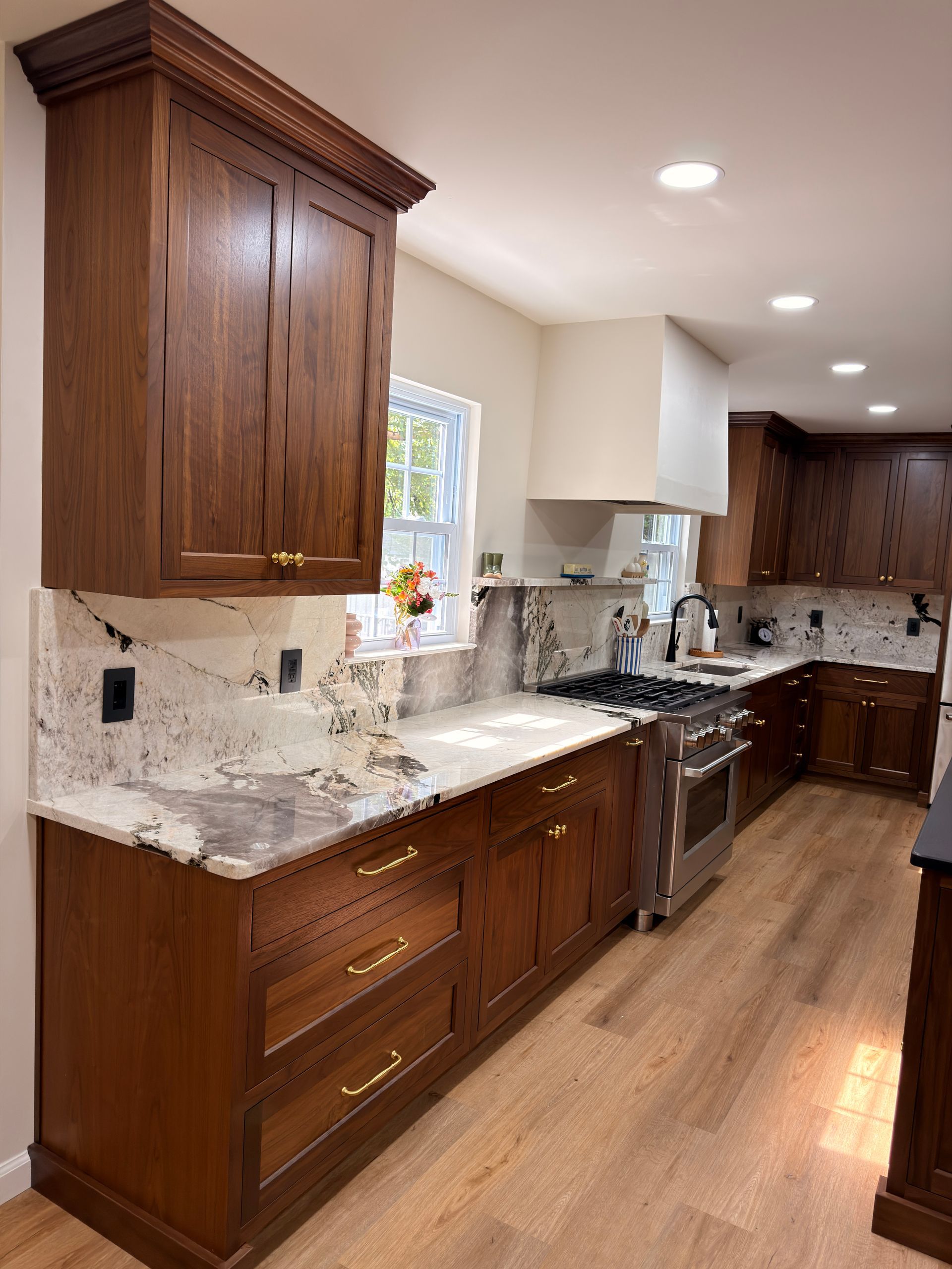 Modern kitchen with dark wood cabinets, white countertops, stainless steel appliances, and hardwood floors