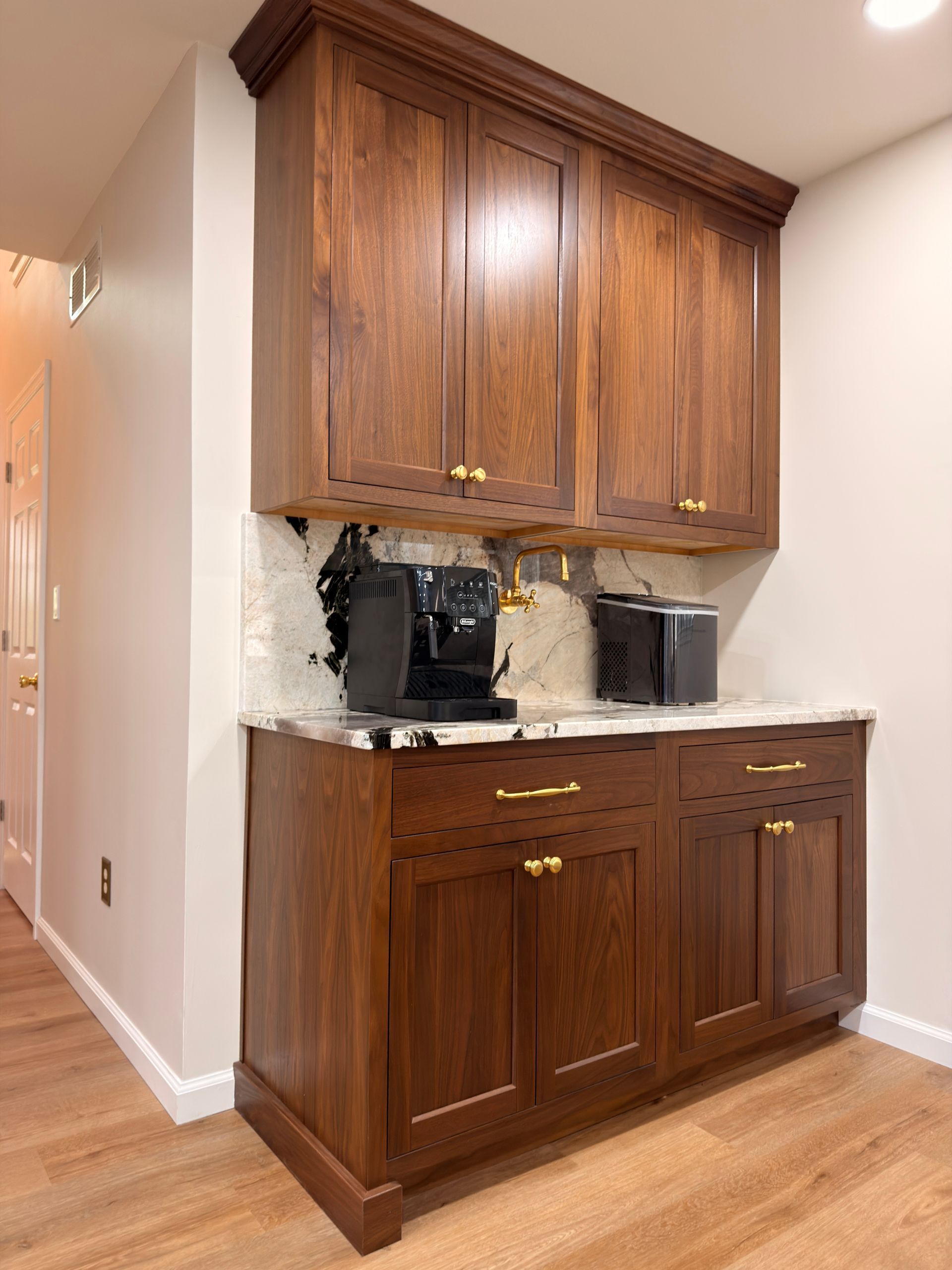 Built-in wooden coffee station with cabinets and countertop in a hallway nook