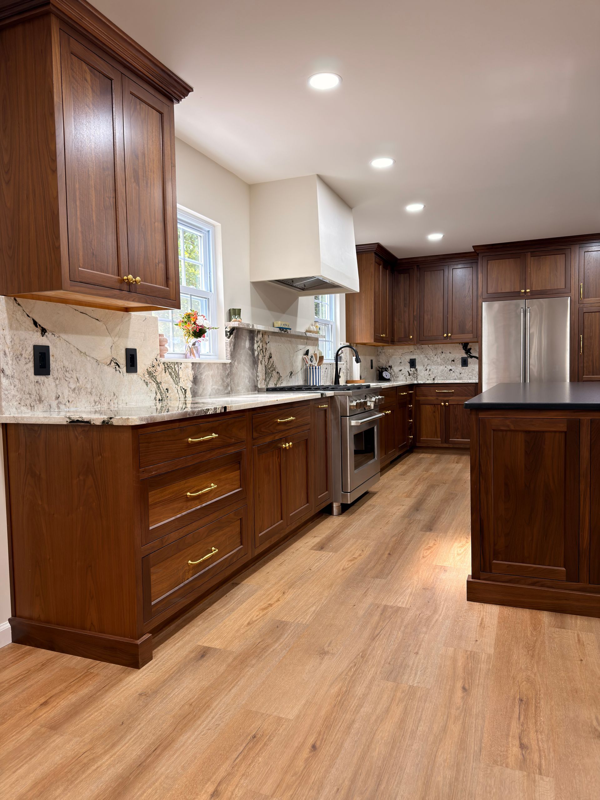 Modern kitchen with dark wood cabinets, stainless steel appliances, light tile backsplash, and hardwood floors