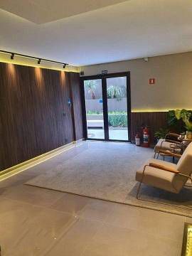 Uma área de recepção moderna e minimalista com paredes revestidas de madeira, uma grande porta envidraçada e duas cadeiras de cor clara.