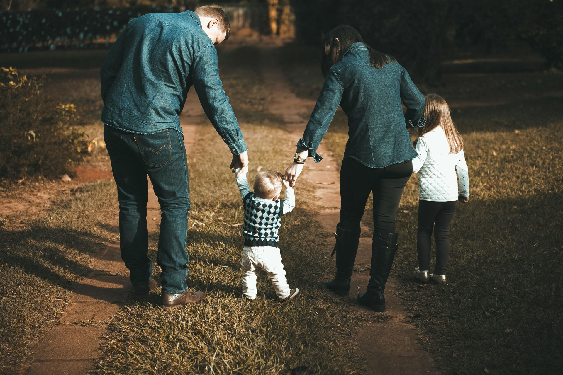 Two adults and two children walking hand in hand on a dimly lit path at night