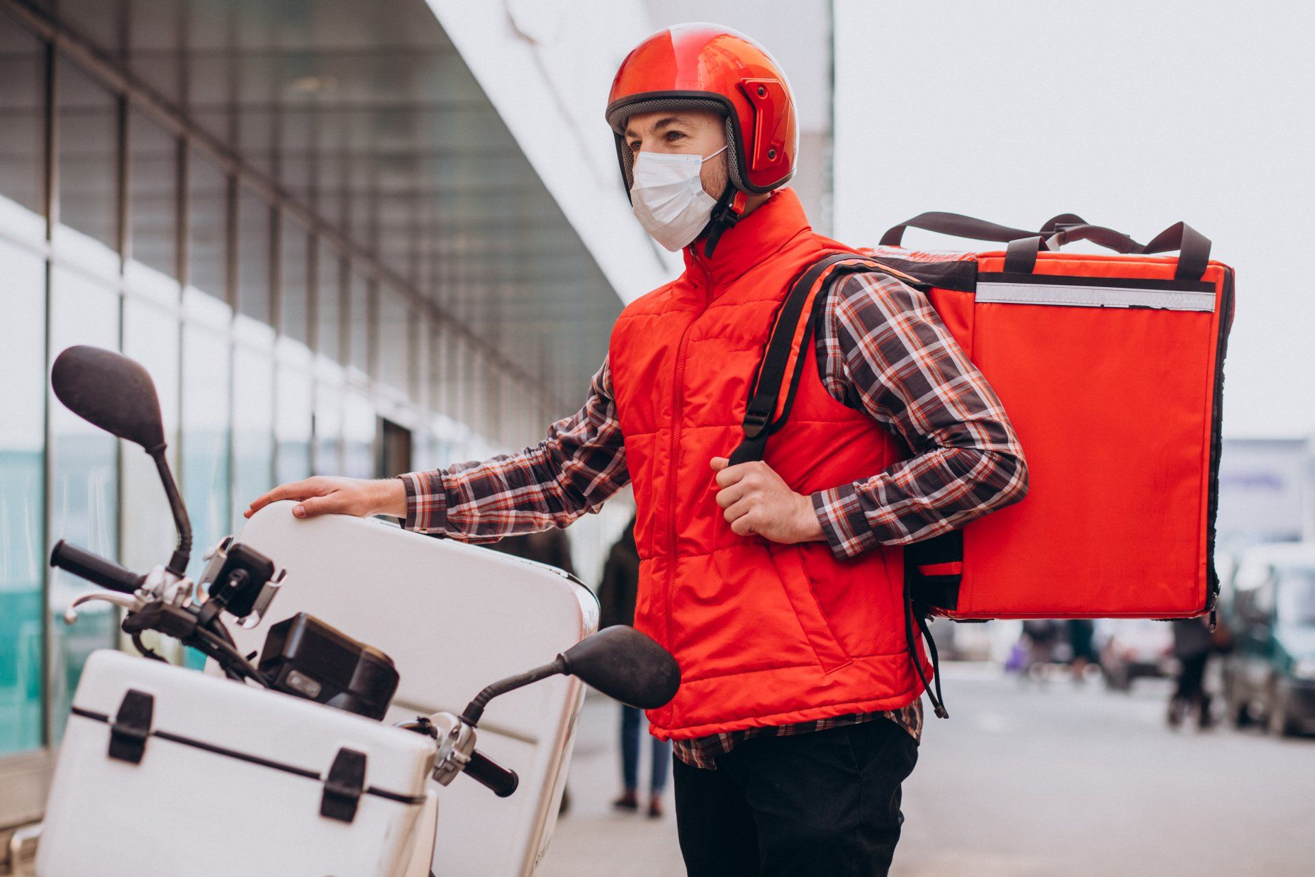 Repartidor de alimentos conduciendo scooter con caja con comida y máscara con máscara