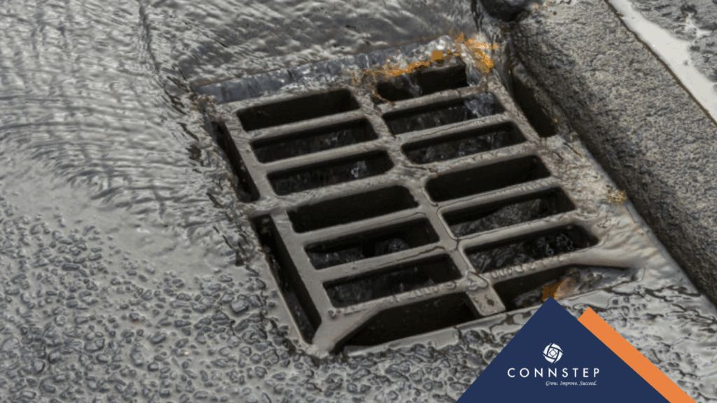 Drain grate on a dark surface with flowing water.