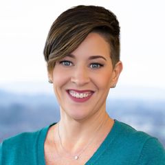 A portrait of Amanda Beaulieu, Media Inquiries at CONNSTEP, a woman with short hair, smiling. Wearing teal top and necklace. Blurred cityscape background.