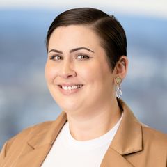 A portrait of Nichole Lynn, Business Services Associate at CONNSTEP, smiling, wearing a beige blazer and dangling earrings.