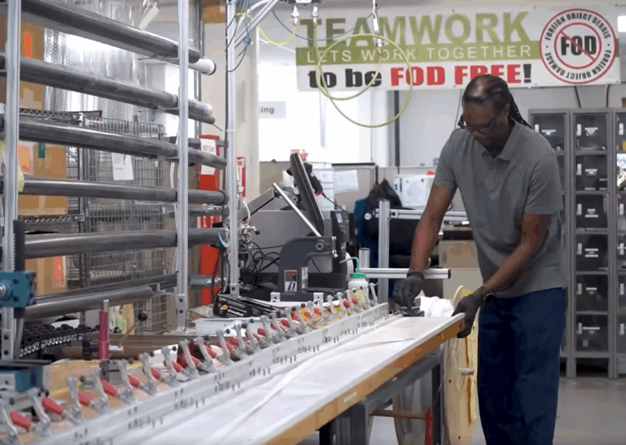 Man operating machinery in a factory, with a sign reading